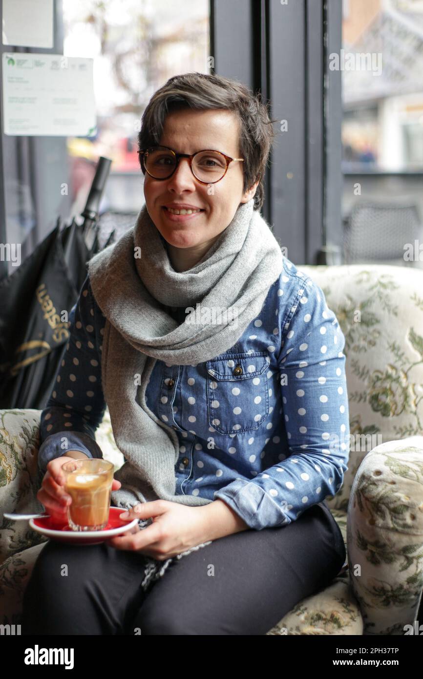 Ragazza seduta in una caffetteria che guarda fuori Foto Stock