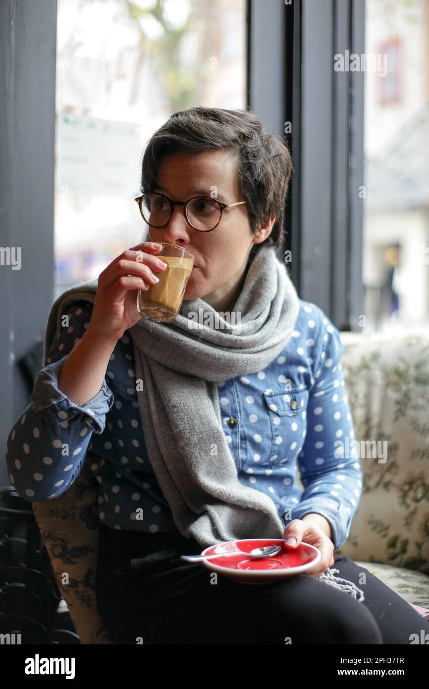 Ragazza seduta in una caffetteria che guarda fuori Foto Stock