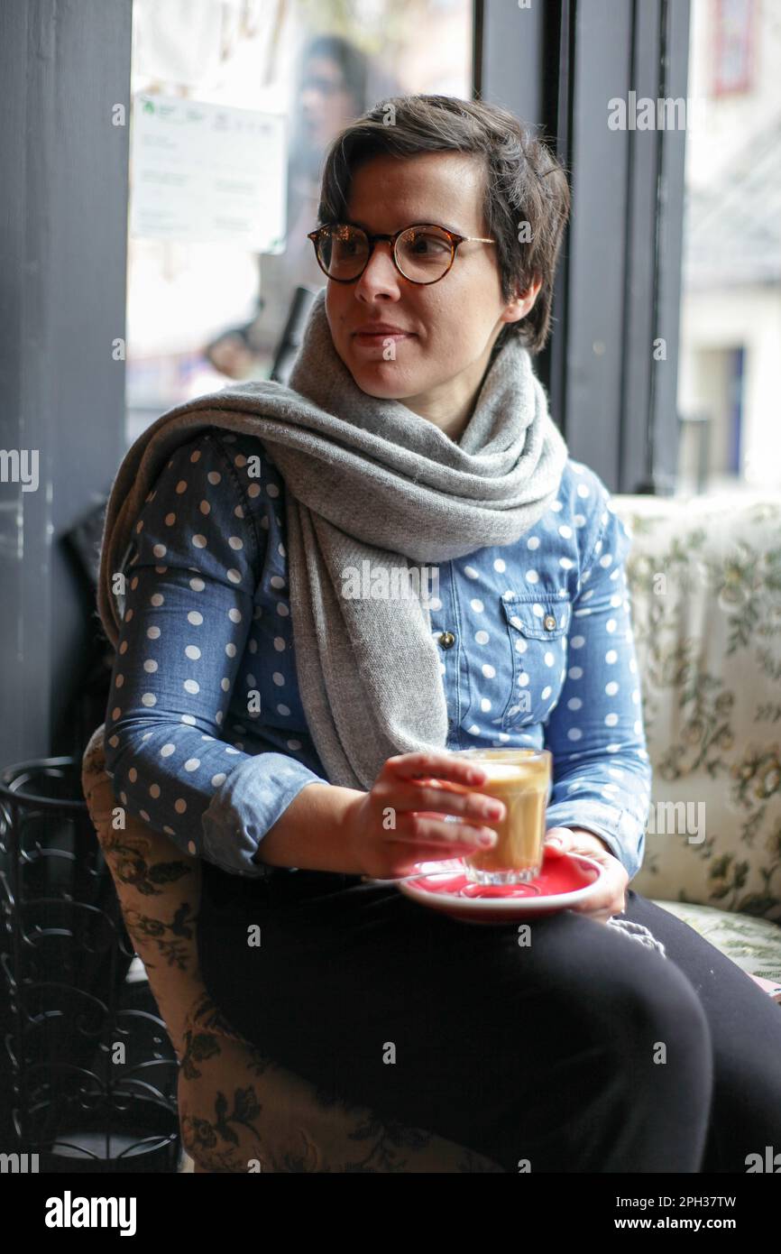 Ragazza seduta in una caffetteria che guarda fuori Foto Stock
