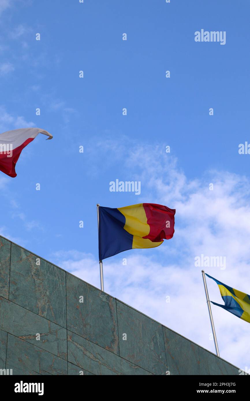 La bandiera rumena sventolava in cima all'edificio con altre bandiere delle Nazioni Foto Stock