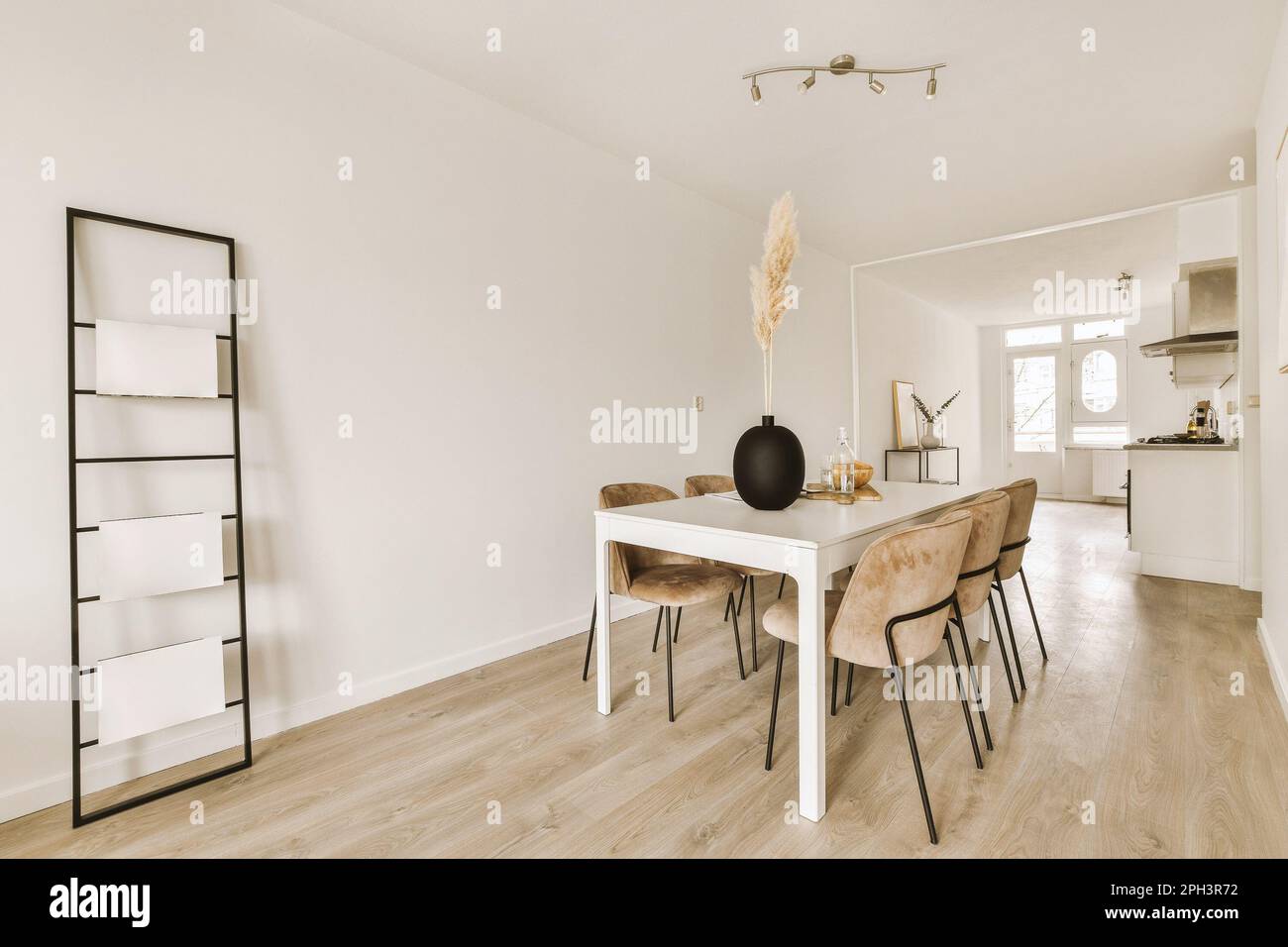 un tavolo da pranzo e sedie in un soggiorno con pareti bianche, pavimento in legno e pavimenti in legno chiaro Foto Stock
