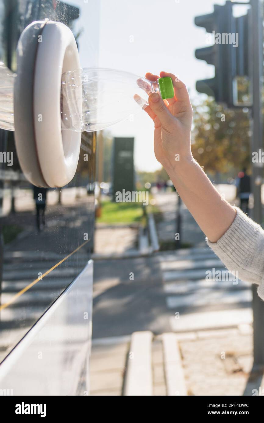 Donna utilizza una macchina self-service per ricevere bottiglie di plastica usate e lattine su una strada cittadina. Foto di alta qualità Foto Stock