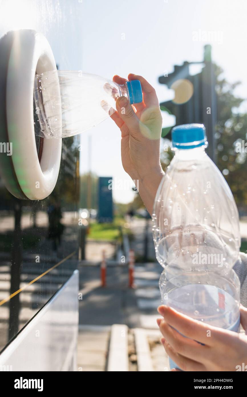 Donna utilizza una macchina self-service per ricevere bottiglie di plastica usate e lattine su una strada cittadina. Foto di alta qualità Foto Stock