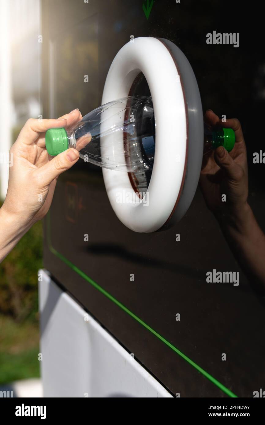 Donna utilizza una macchina self-service per ricevere bottiglie di plastica usate e lattine su una strada cittadina. Foto di alta qualità Foto Stock