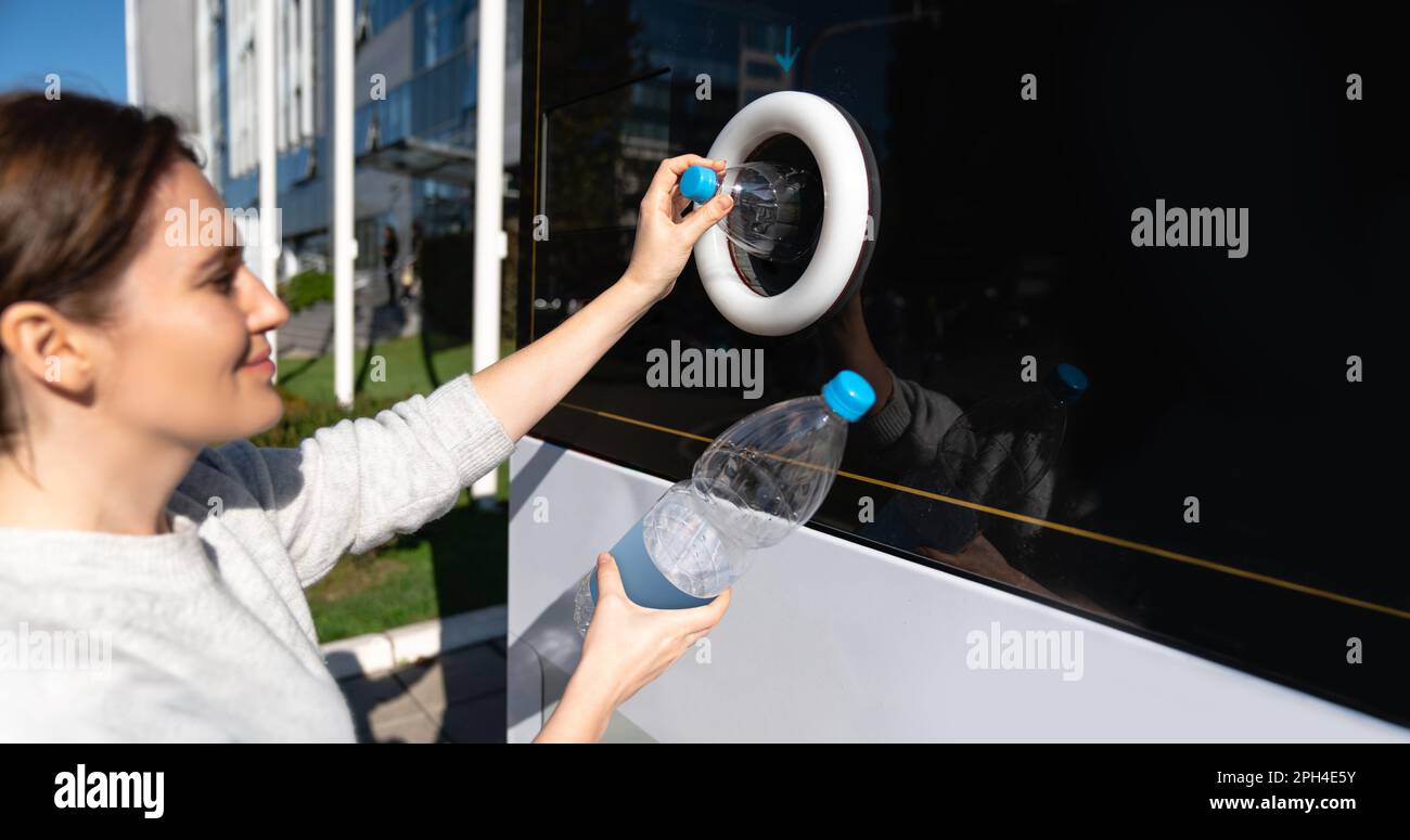 Donna utilizza una macchina self-service per ricevere bottiglie di plastica usate e lattine su una strada cittadina. Foto di alta qualità Foto Stock