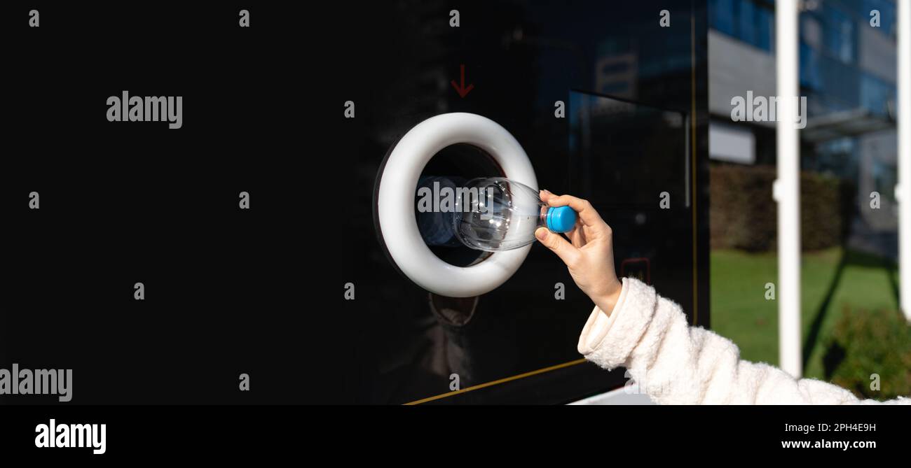 Donna utilizza una macchina self-service per ricevere bottiglie di plastica usate e lattine su una strada cittadina. Foto di alta qualità Foto Stock