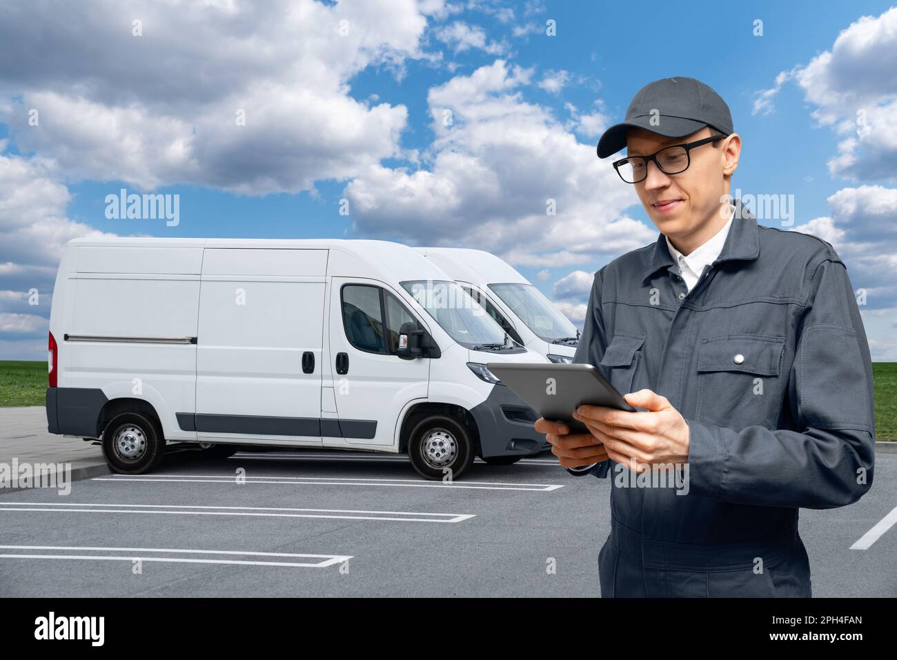Manager con un tablet digitale sullo sfondo dei furgoni. Gestione della flotta. Foto Stock
