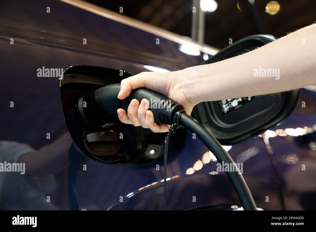 Donna che tiene la spina della stazione di ricarica per auto elettriche. Foto di alta qualità Foto Stock