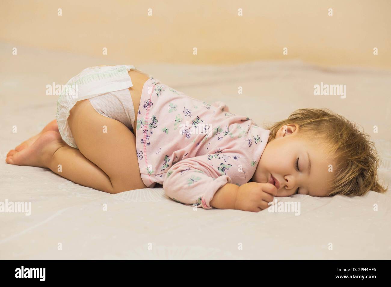 Ragazza cute del bambino che dorme divertente sulla pancia Foto Stock