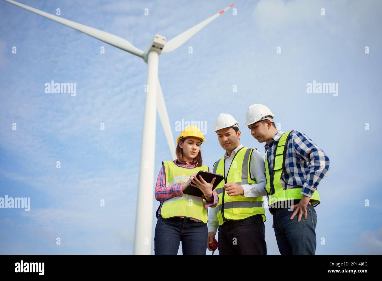 Team di ingegneri asiatici che discutono e controllano le turbine nella fattoria di turbine eoliche. Tecnologia e sostenibilità delle energie rinnovabili. Foto Stock Team di ingegneri asiatici che discutono e controllano le turbine nella fattoria di turbine eoliche. Tecnologia e sostenibilità delle energie rinnovabili. Foto Stock