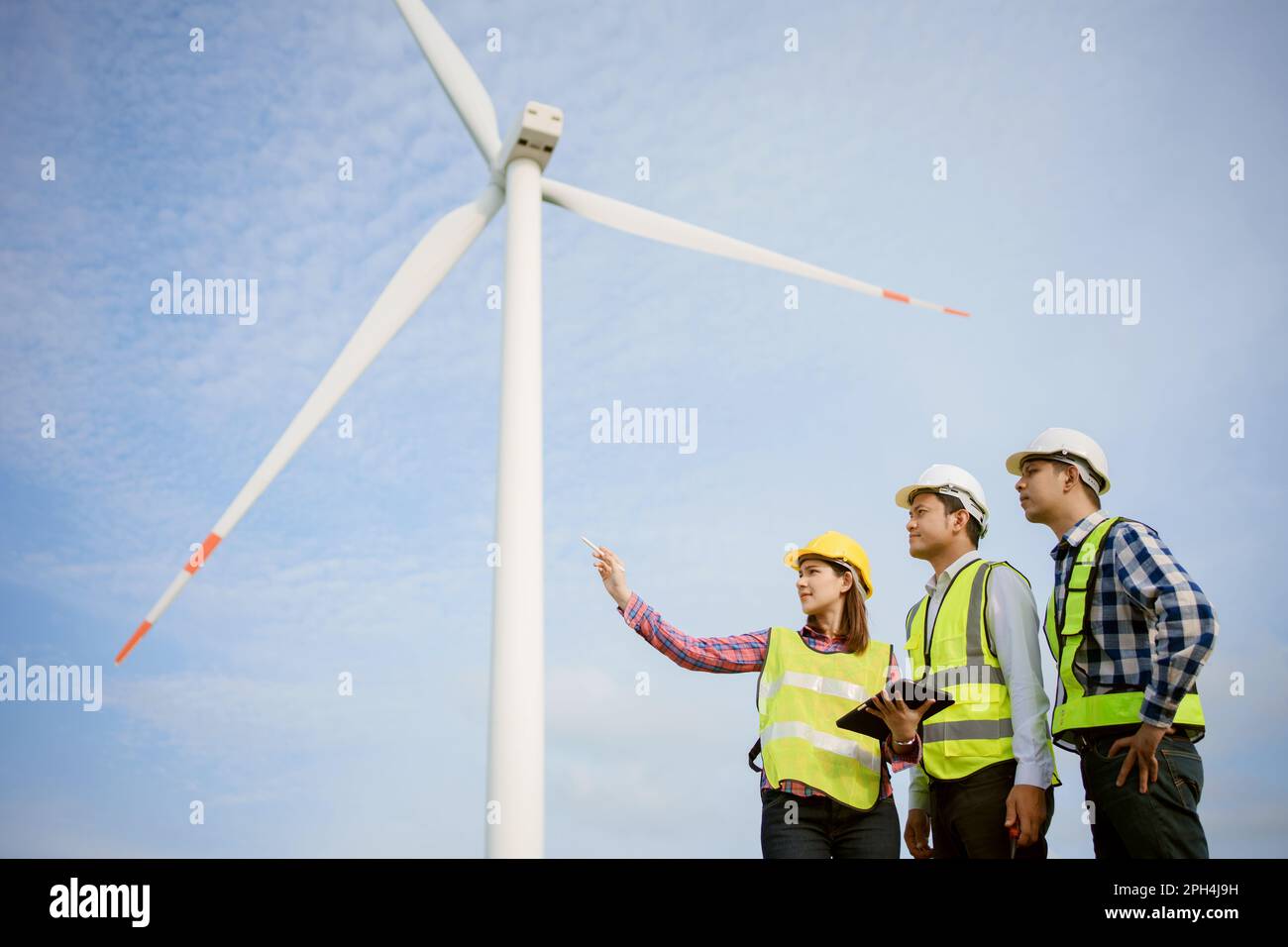 Team di ingegneri asiatici che discutono e controllano le turbine nella fattoria di turbine eoliche. Tecnologia e sostenibilità delle energie rinnovabili. Foto Stock Team di ingegneri asiatici che discutono e controllano le turbine nella fattoria di turbine eoliche. Tecnologia e sostenibilità delle energie rinnovabili. Foto Stock