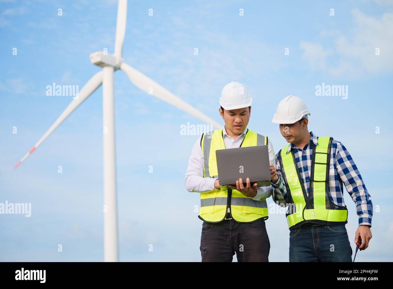Due ingegneri asiatici che discutono e controllano le turbine nella fattoria di turbine eoliche. Tecnologia e sostenibilità delle energie rinnovabili. Foto Stock Due ingegneri asiatici che discutono e controllano le turbine nella fattoria di turbine eoliche. Tecnologia e sostenibilità delle energie rinnovabili. Foto Stock
