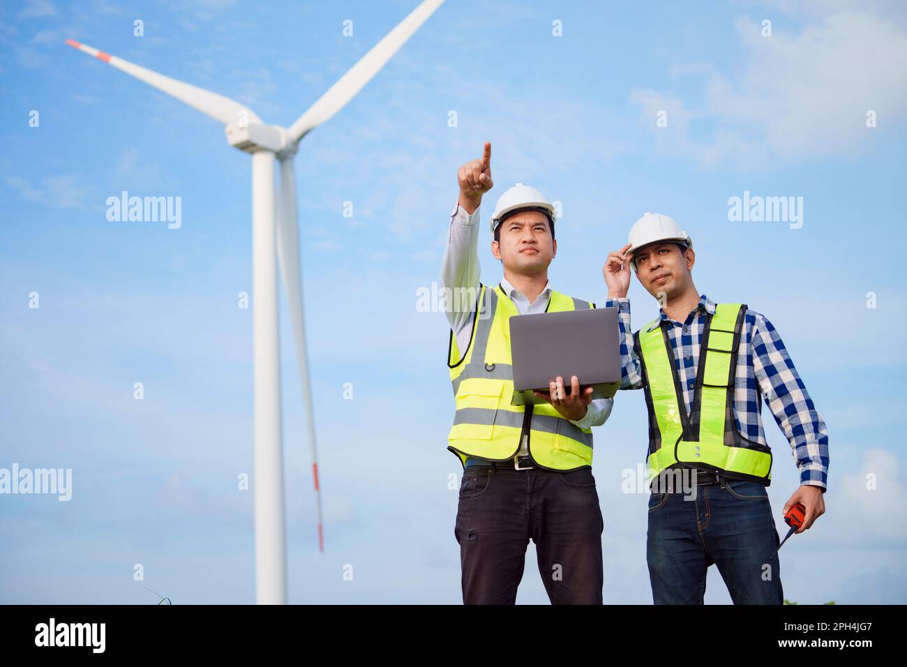 Due ingegneri asiatici che discutono e controllano le turbine nella fattoria di turbine eoliche. Tecnologia e sostenibilità delle energie rinnovabili. Foto Stock Due ingegneri asiatici che discutono e controllano le turbine nella fattoria di turbine eoliche. Tecnologia e sostenibilità delle energie rinnovabili. Foto Stock