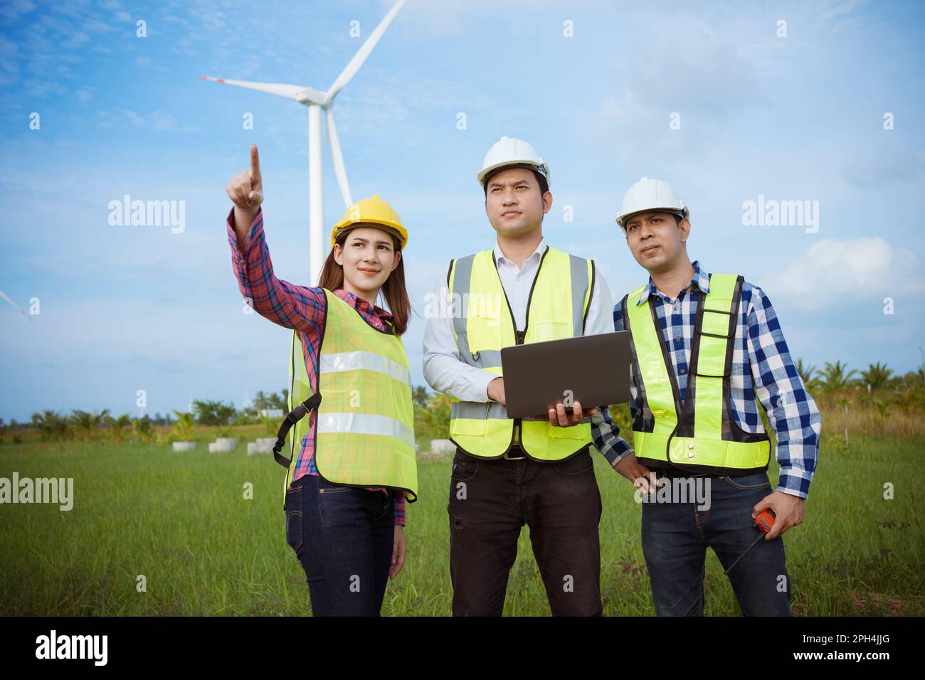 Team di ingegneri asiatici che discutono e controllano le turbine nella fattoria di turbine eoliche. Tecnologia e sostenibilità delle energie rinnovabili. Foto Stock Team di ingegneri asiatici che discutono e controllano le turbine nella fattoria di turbine eoliche. Tecnologia e sostenibilità delle energie rinnovabili. Foto Stock