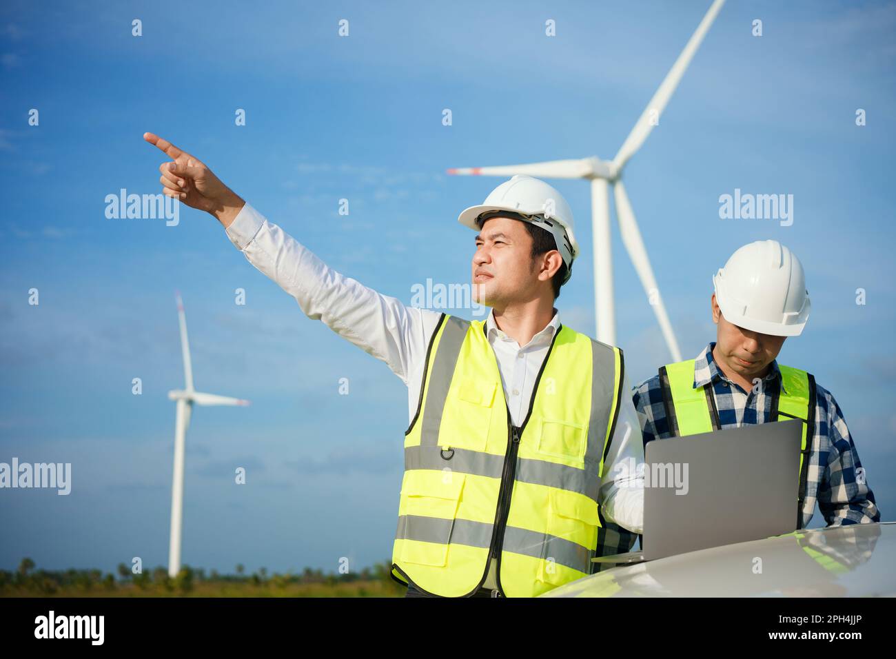 Due ingegneri asiatici che discutono e controllano le turbine nella fattoria di turbine eoliche. Tecnologia e sostenibilità delle energie rinnovabili. Foto Stock Due ingegneri asiatici che discutono e controllano le turbine nella fattoria di turbine eoliche. Tecnologia e sostenibilità delle energie rinnovabili. Foto Stock