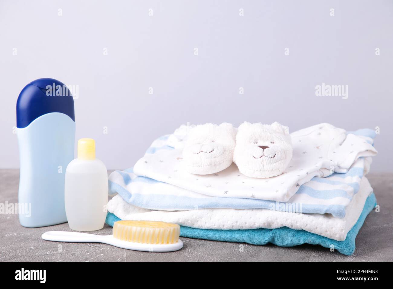 Set di vestiti per bambini con pettine e ciabatte bianche dopo una doccia su sfondo grigio Foto Stock
