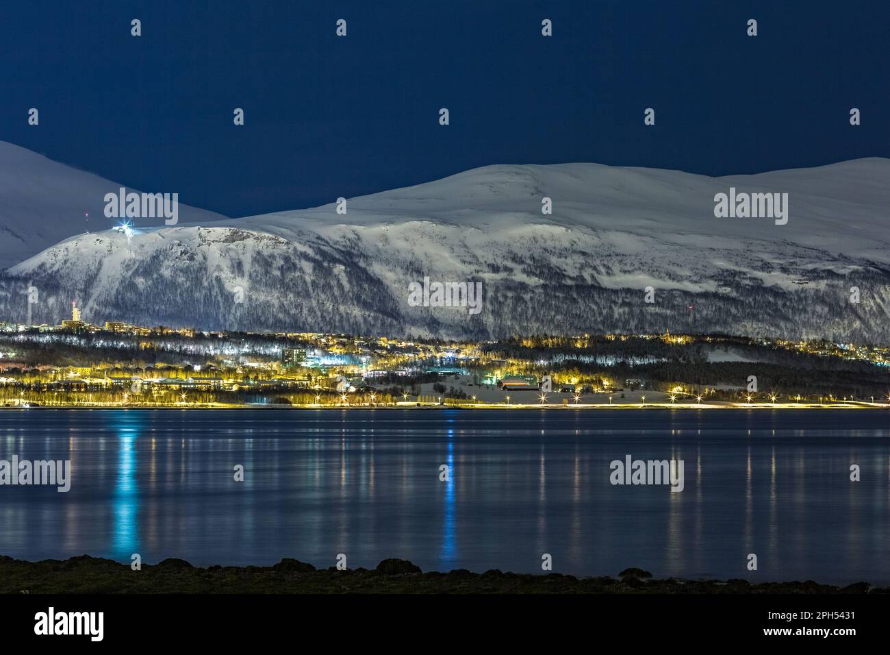 Foto notturna fredda a lunga esposizione della città norvegese di Tromsø, Norvegia settentrionale. 30 secondi. Montagne coperte di neve e acqua sfocata movimento Foto Stock