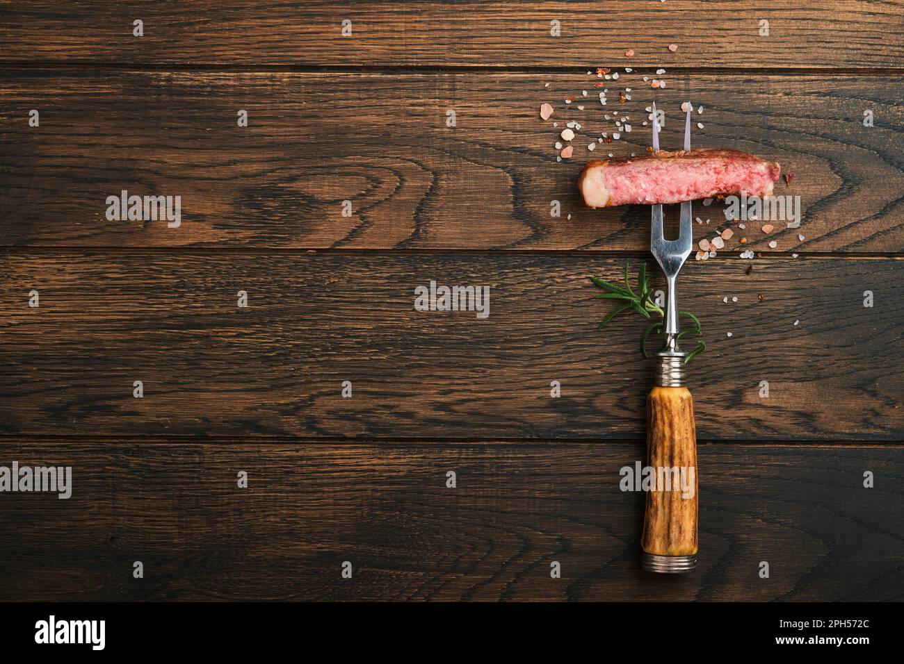 Bistecche all'osso T. Fette di carne di manzo grigliata bistecca alla griglia sulla forchetta di carne su sfondo di legno scuro bruciato con spazio copia per il testo. Vista dall'alto. Simulazione Foto Stock