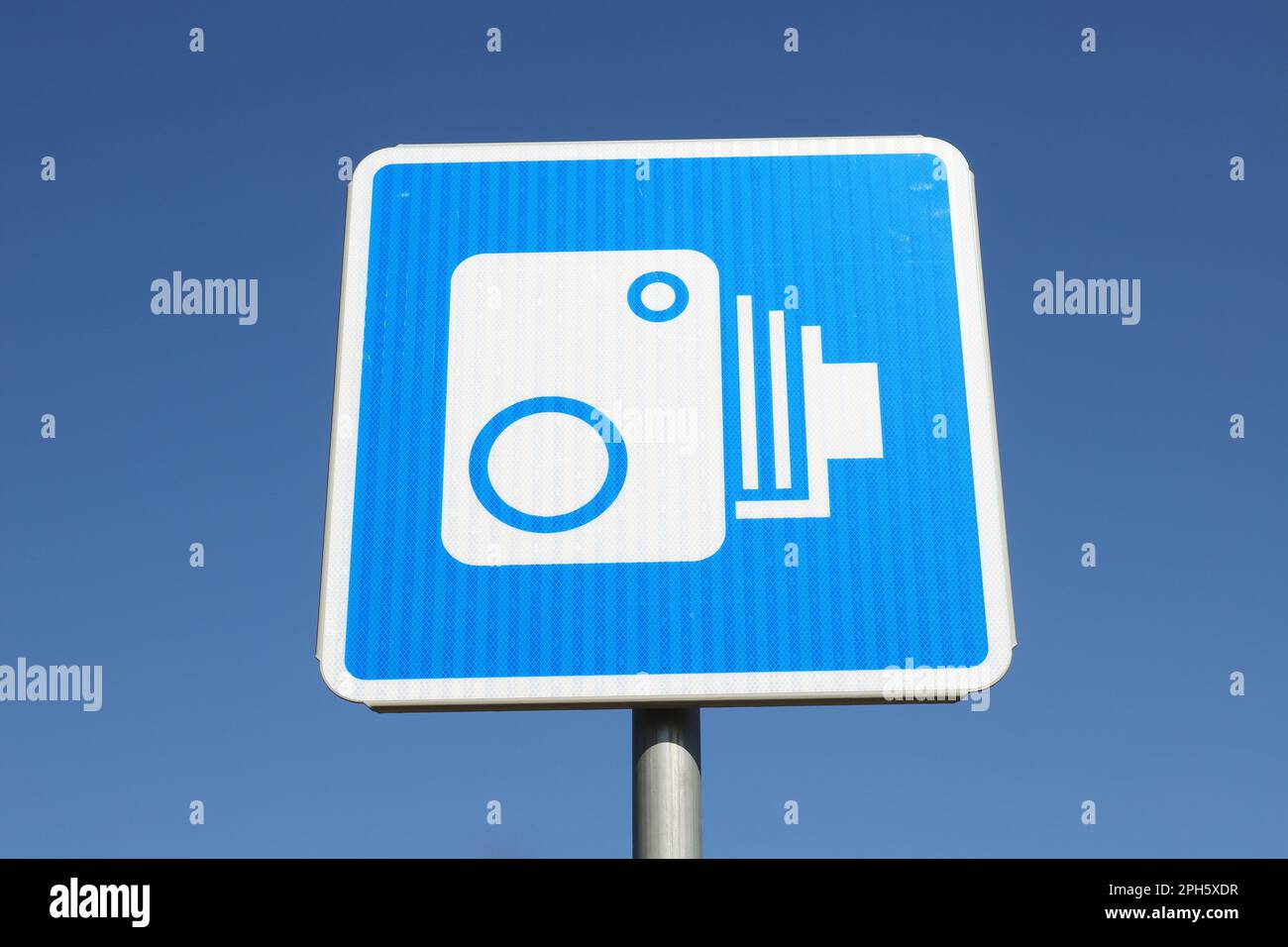 Vista ad angolo basso di un segnale stradale finlandese con un simbolo per la telecamera di sorveglianza automatica del traffico contro il cielo blu chiaro. Foto Stock