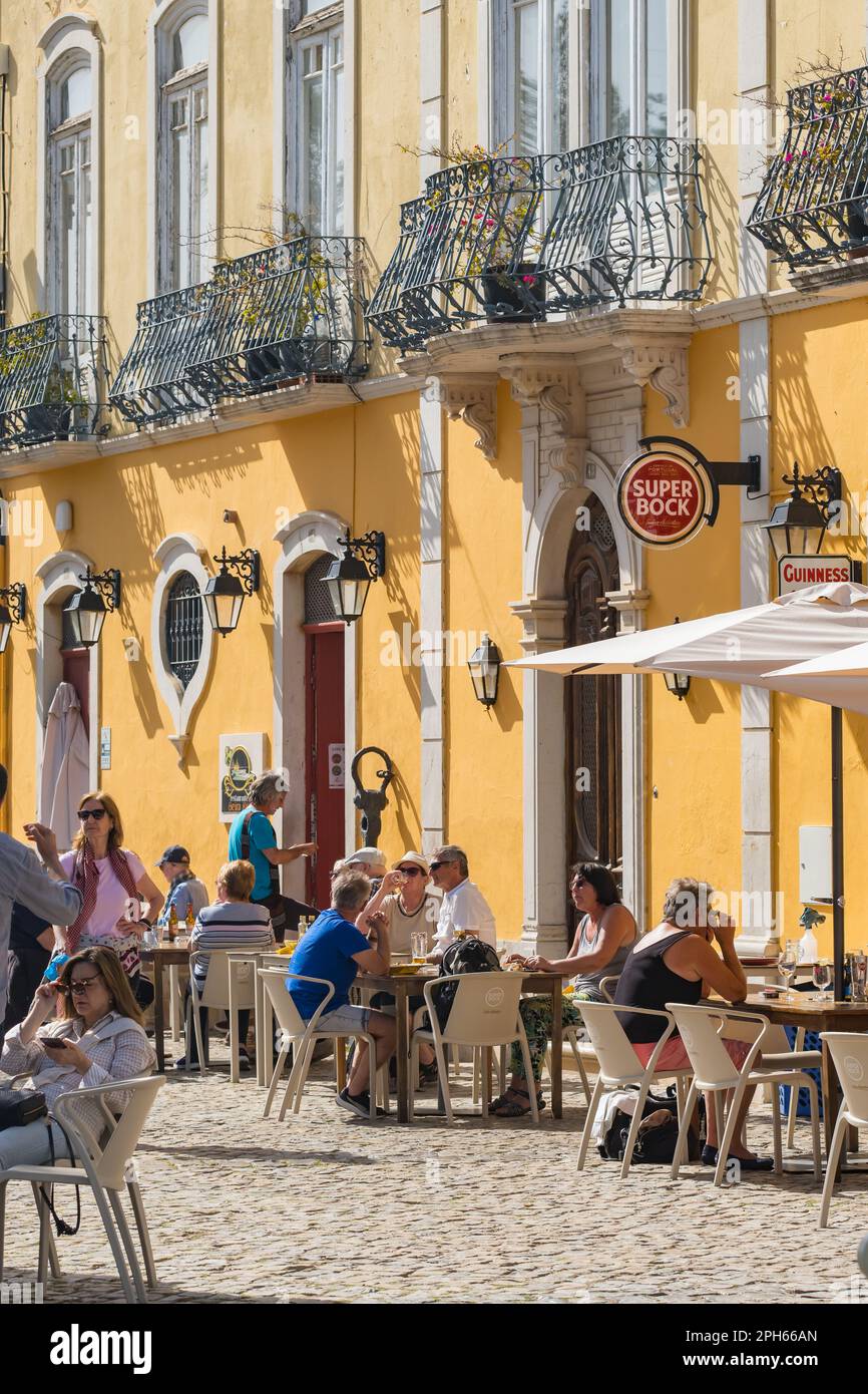 Accoglienti caffè all'aperto lungo il fiume nella città di Tavira, dove la gente mangia e beve in una giornata di sole primaverile. Foto Stock