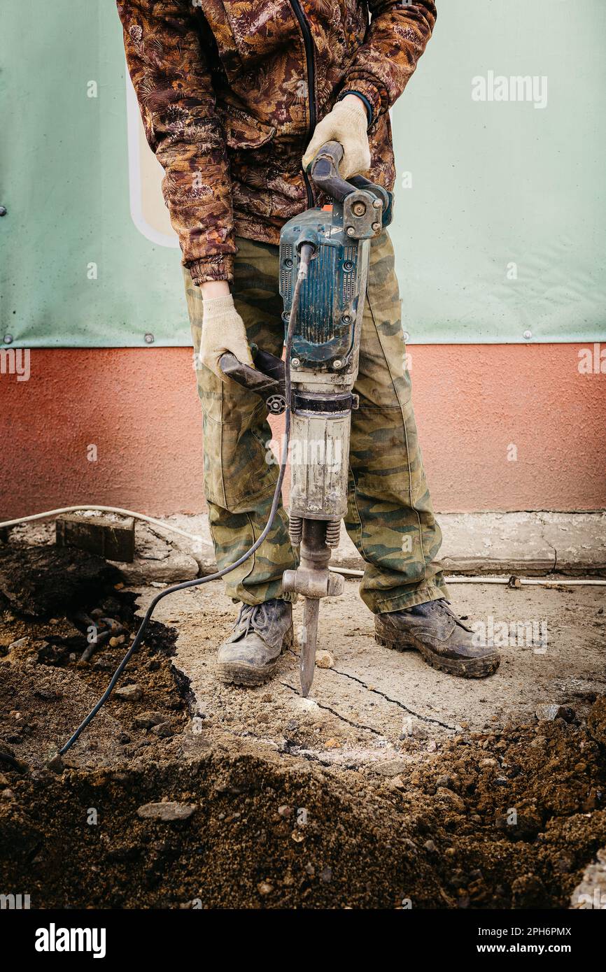 Costruttore maschile che lavora con un martello a martello battendo una superficie dura Foto Stock