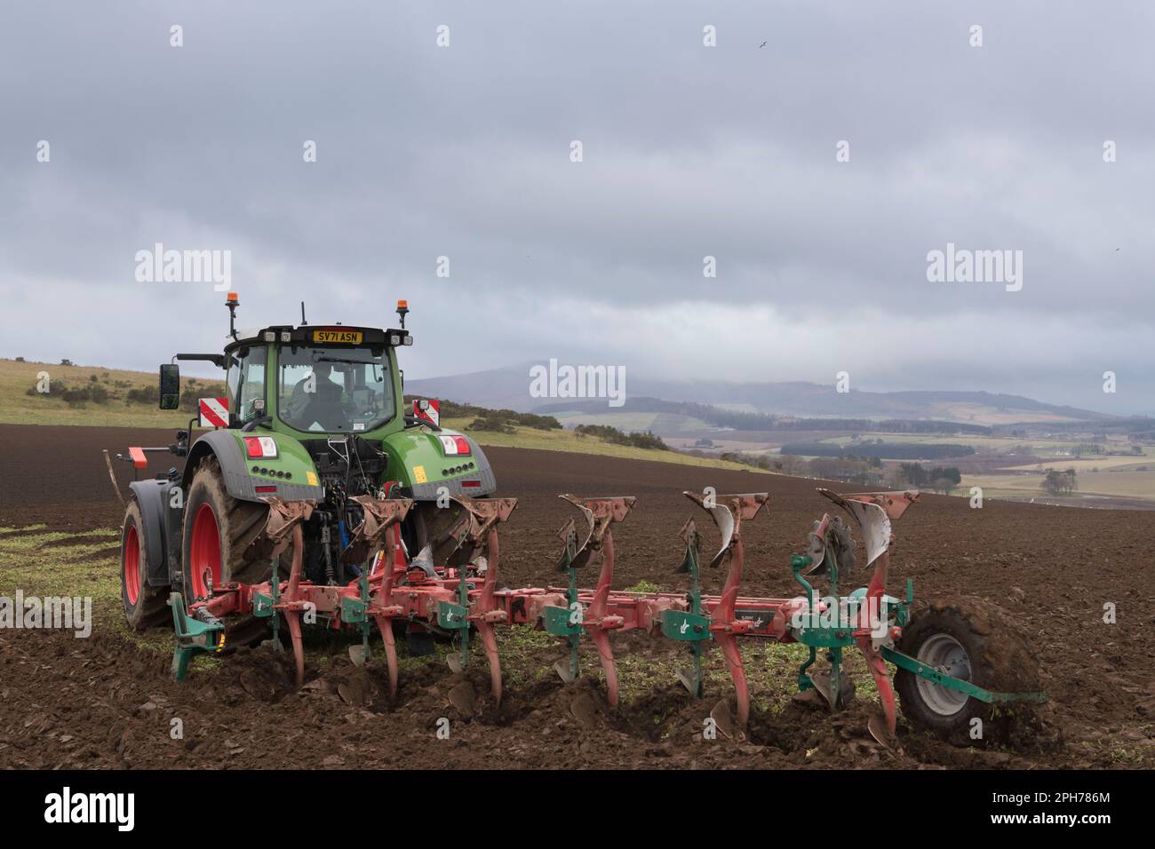 Un'aratura del trattore Fendt con un'aratro reversibile Kverneland con vista del paesaggio dell'Aberdeenshire in primavera in una mattinata overcast Foto Stock