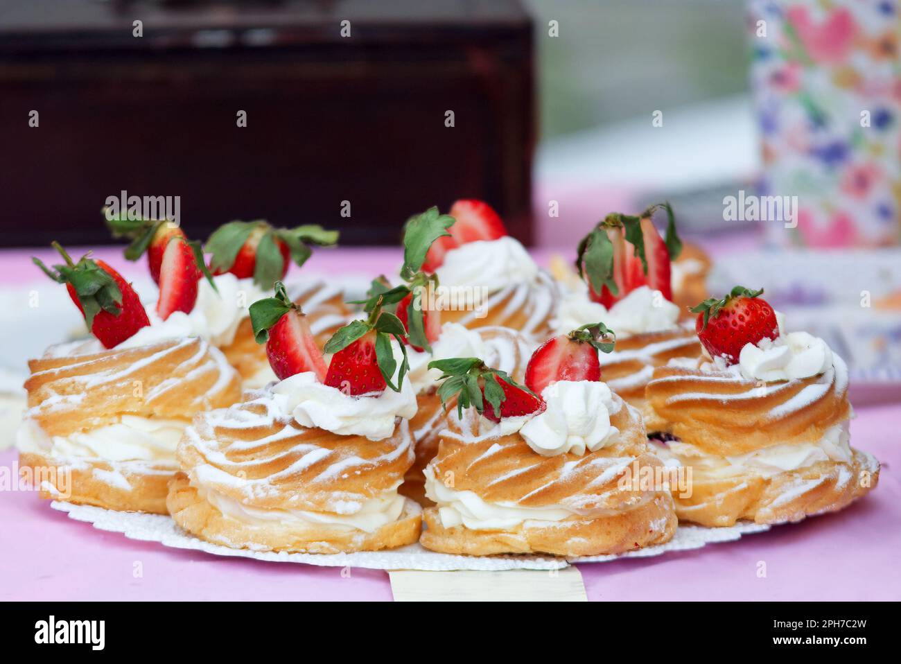 Vassoio pieno di corone con crema di tuorlo e panna montata sul tavolo della pasticceria presso il mercato alimentare di strada degli agricoltori. Primo piano delle corone w Foto Stock