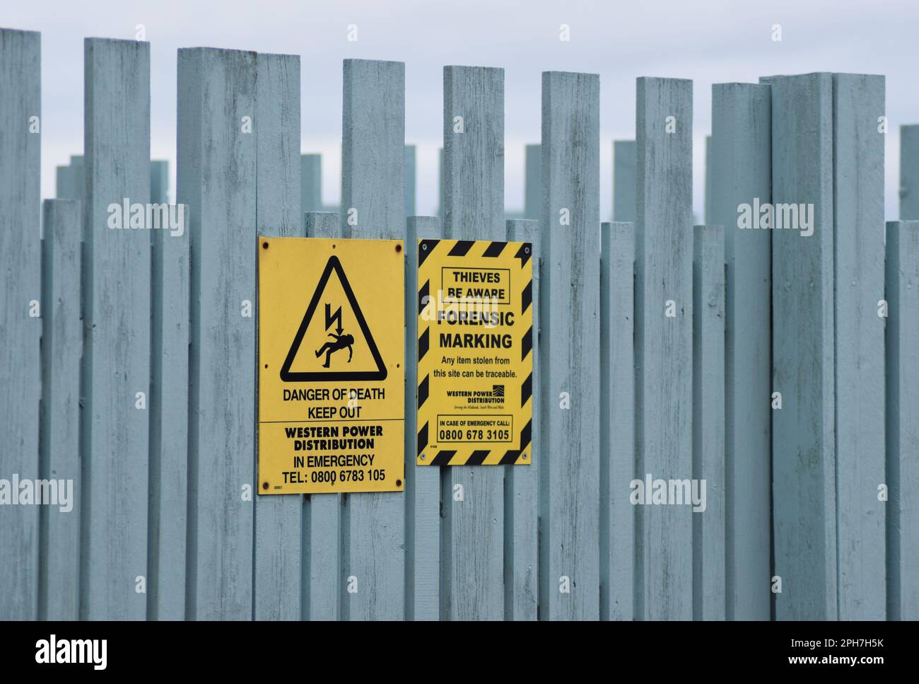 Avvisi sulla recinzione di una sottostazione elettrica, con spazio per le copie. Foto Stock