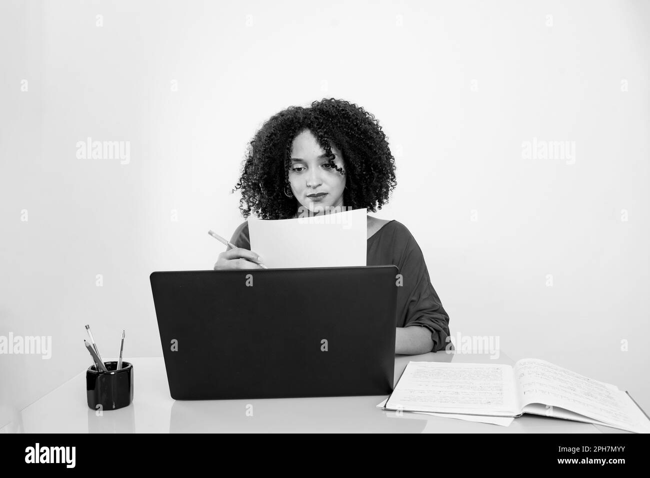 Ritratto in bianco e nero di una giovane donna d'affari che lavora con un computer portatile. Ufficio domestico. Foto Stock