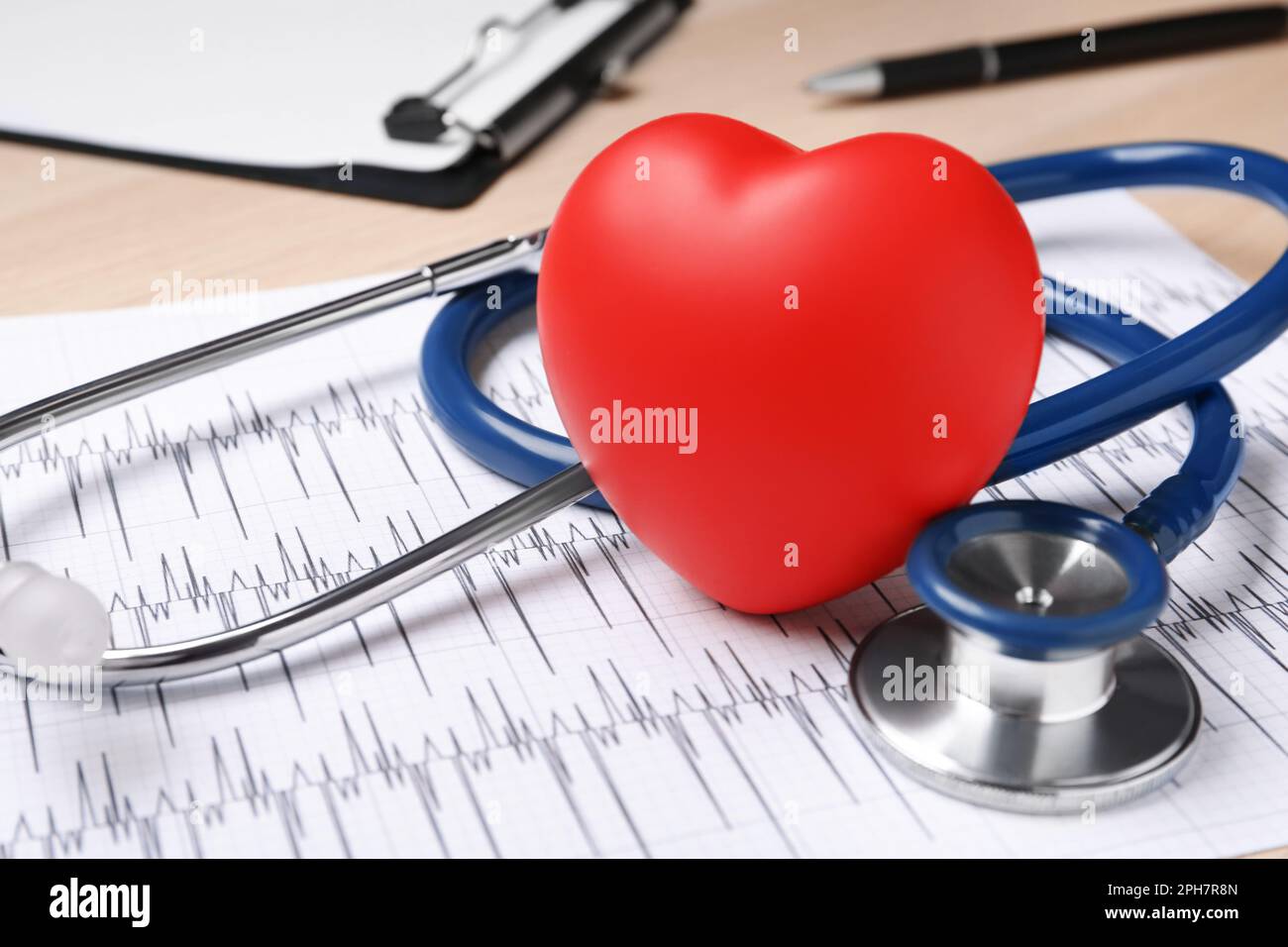 Stetoscopio, cardiogramma e cuore decorativo rosso su sfondo ligneo, primo piano. Concetto di cardiologia Foto Stock