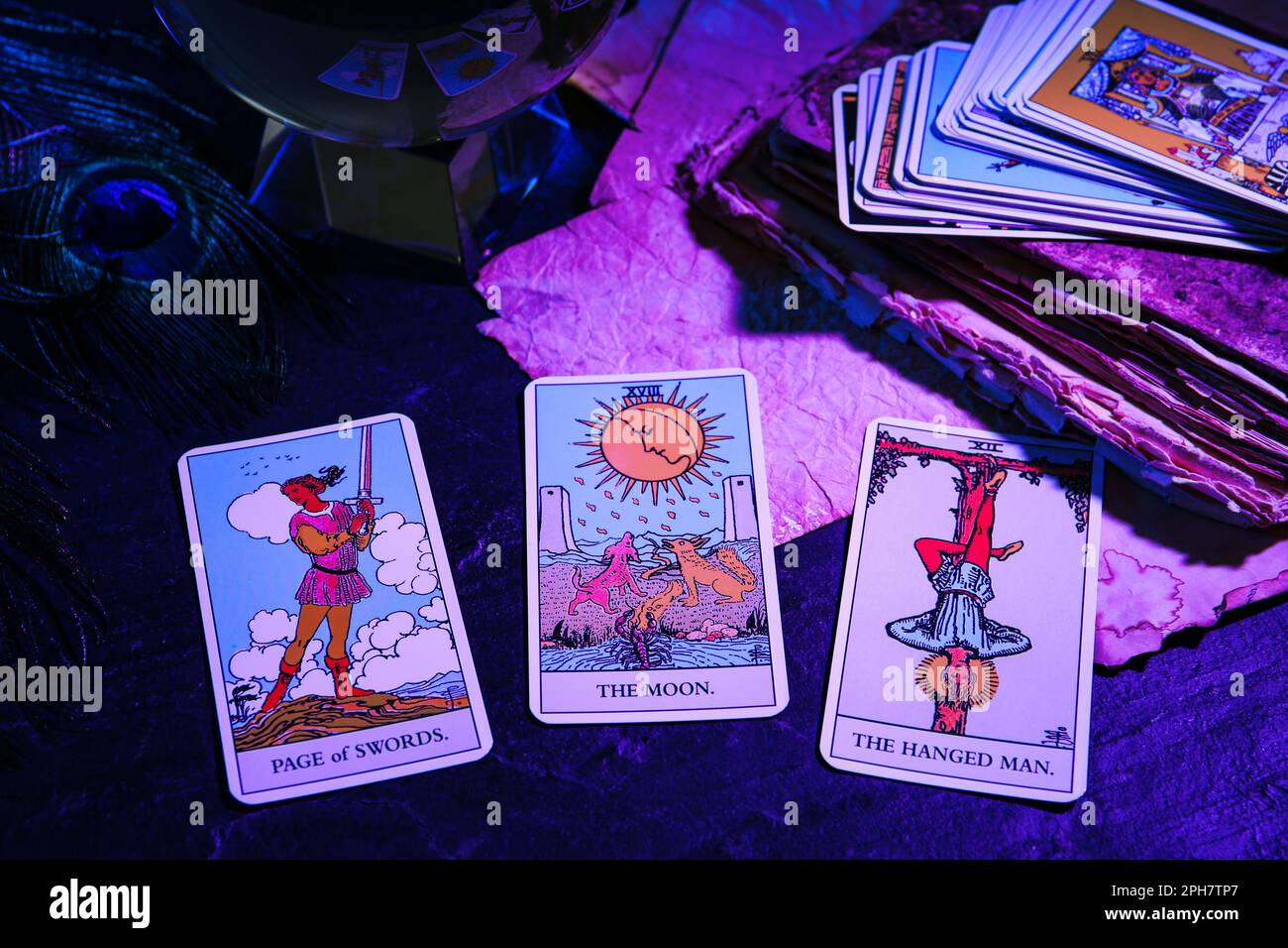 Pagina delle spade, carte tar dell'uomo impiccato e della Luna su tavola scura, colore tonico Foto Stock