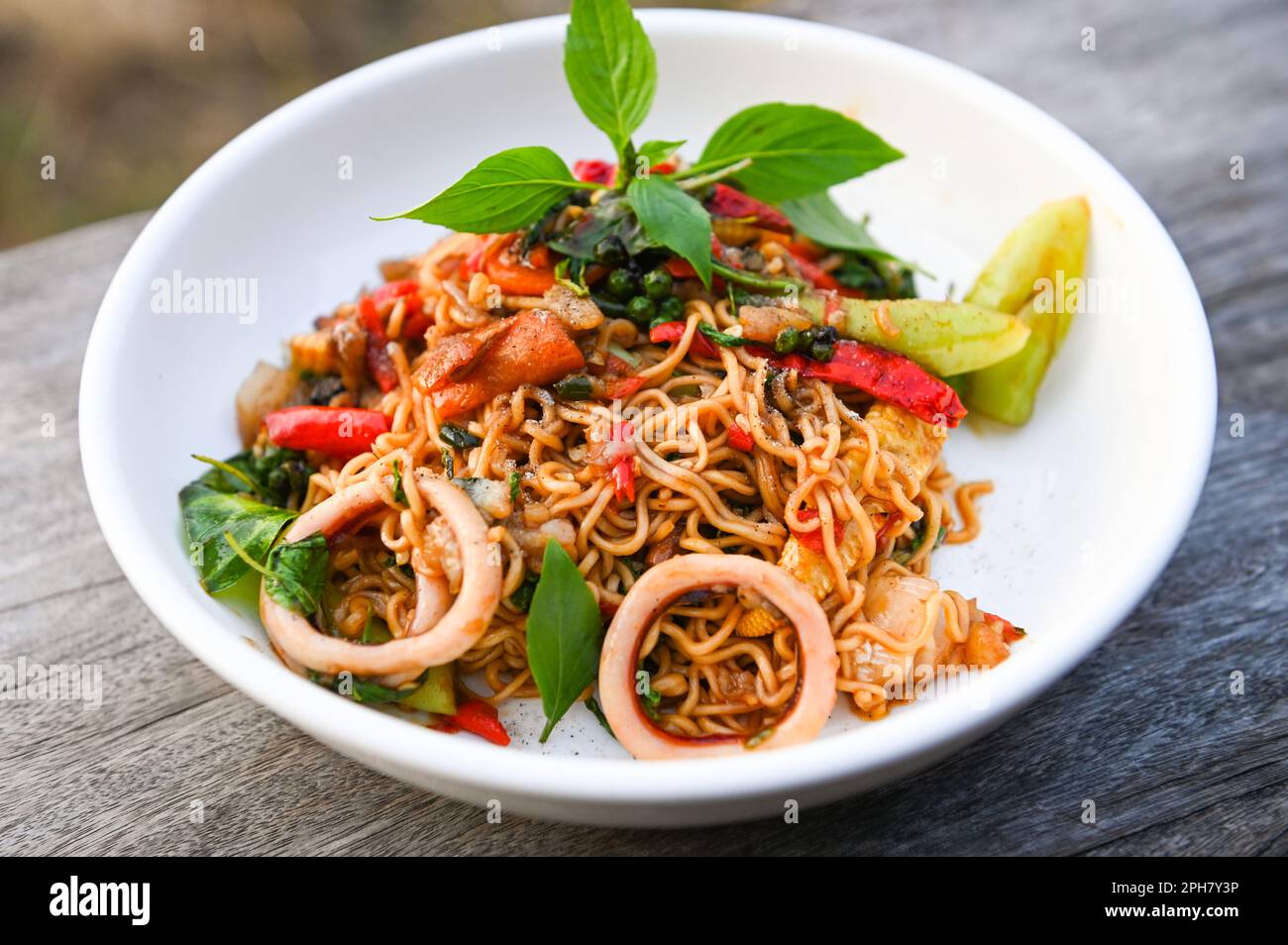 piatto di noodles con noodles istantaneo mescolato fritto con verdure erbe speziato saporito appetitoso asiatico noodles mix frutti di mare mescolato calamari fritti con basilico e ch Foto Stock