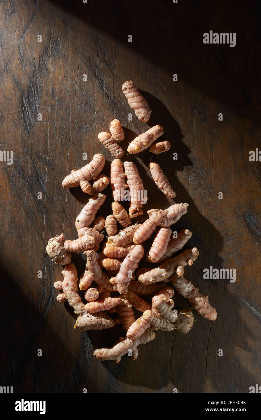 rizomi curcuma puliti o radici su un tavolo di legno, curcuma longa, spezie comunemente utilizzate in cucina e medicina, struttura simile alle radici Foto Stock