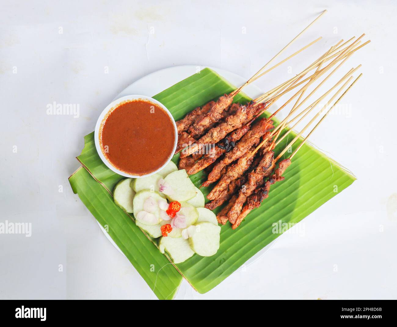 satay di pollo o satay di pollo servito con lontong, torta di riso e salsa di arachidi. servito in congedo di banana Foto Stock