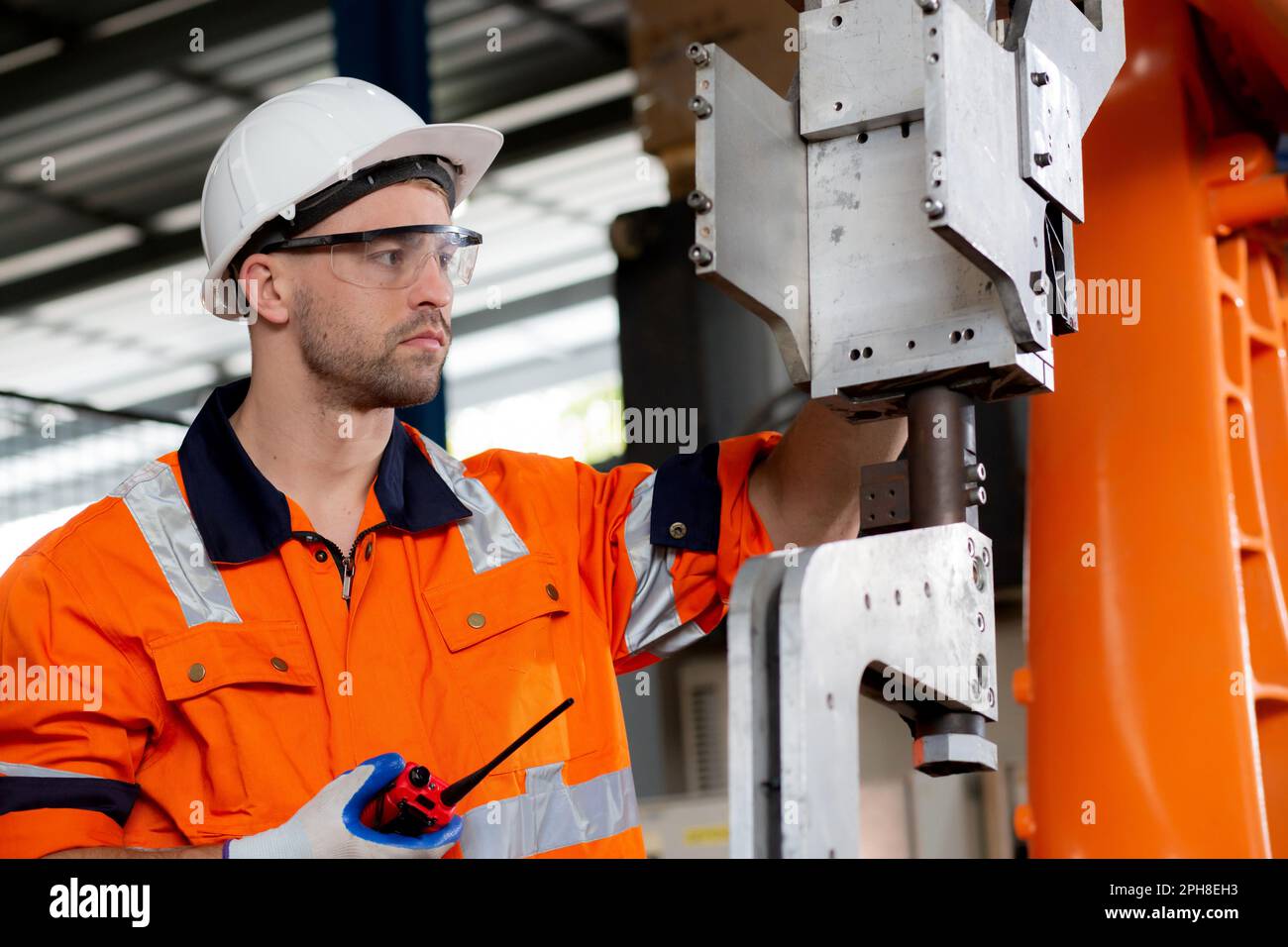 Il giovane ingegnere caucasico uomo ispezione robot armi intelligenza tecnologia e innovazione mentre parlare radio comando in fabbrica, tecnico di controllo e m Foto Stock