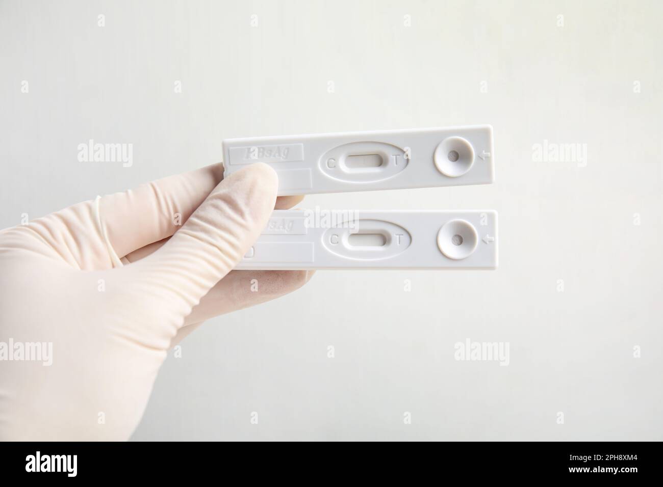 Medico in guanti con test usa e getta express per epatite su sfondo bianco, primo piano Foto Stock