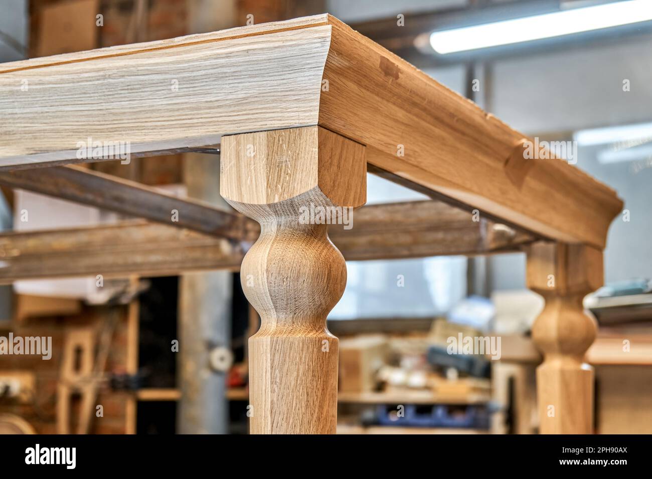 Tavolo da pranzo in legno con gamba intagliata in legno di quercia massello e struttura in metallo processo di costruzione in officina vista ravvicinata Foto Stock