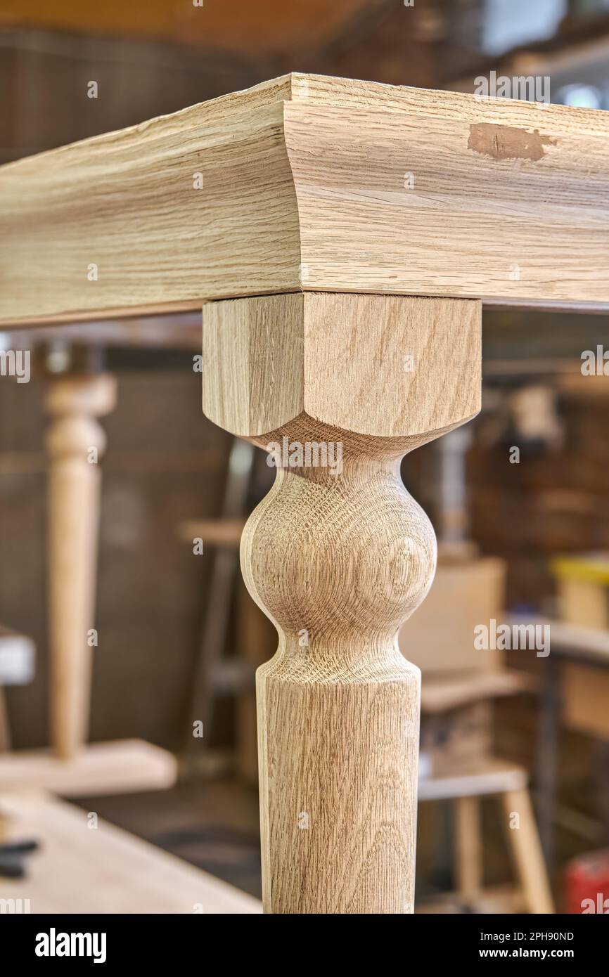 Tavolo da pranzo in legno con gamba intagliata in legno di quercia massello e struttura in metallo processo di costruzione in officina estrema vista closeup Foto Stock