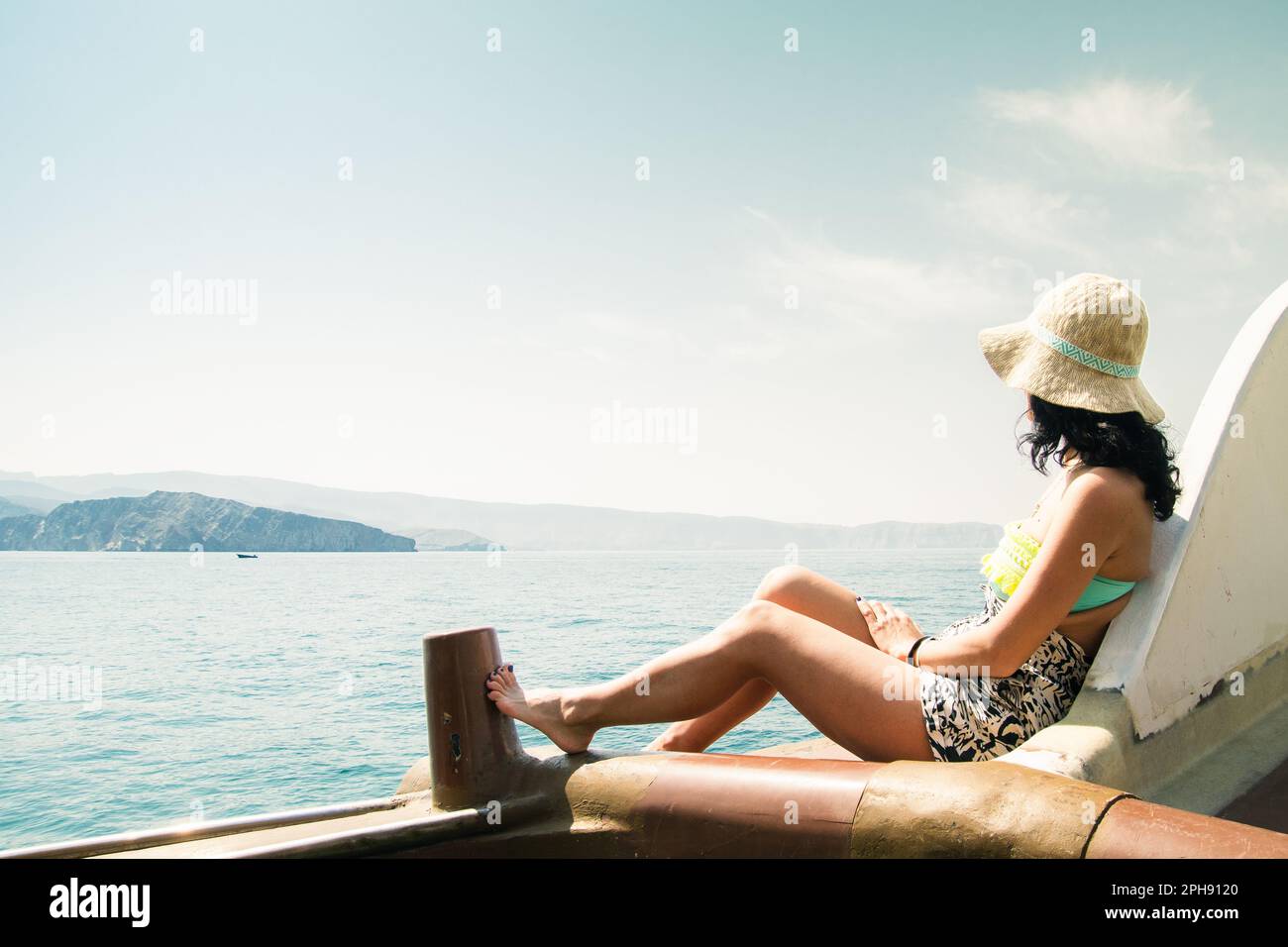 Viaggiatore turistico donna viaggio godendo di un giro su una barca ad alta velocità di fascia alta in vacanza estiva. Elegante bikini nero, capelli lunghi e corpo abbronzato. Oman middl Foto Stock