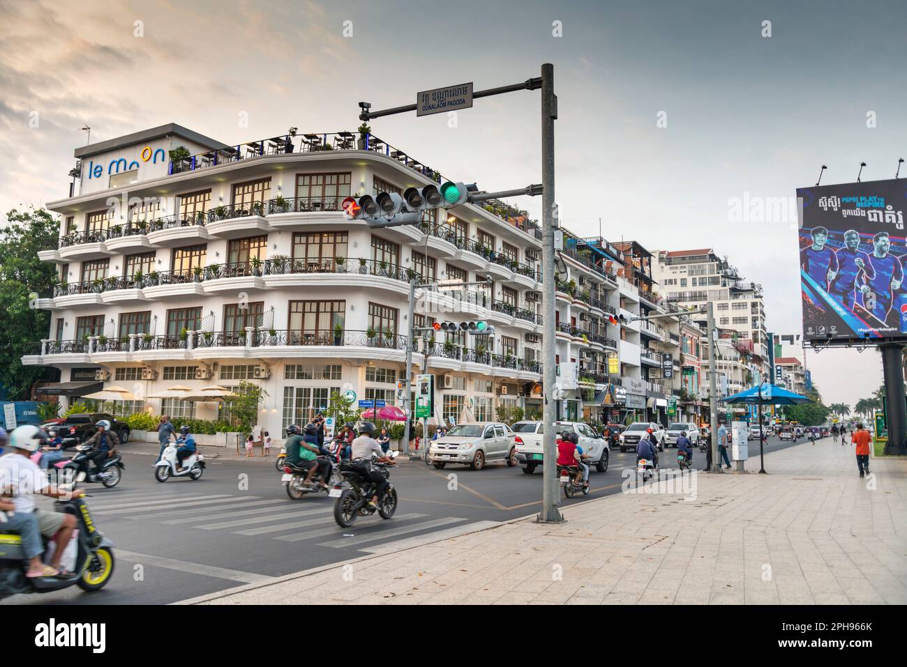 Phnom Penh, Cambogia-Dicembre 23rd 2022: Molte moto, automobili e moto-risciò passano edifici in stile coloniale francese, lungo il lungomare di Tonle SAP Foto Stock