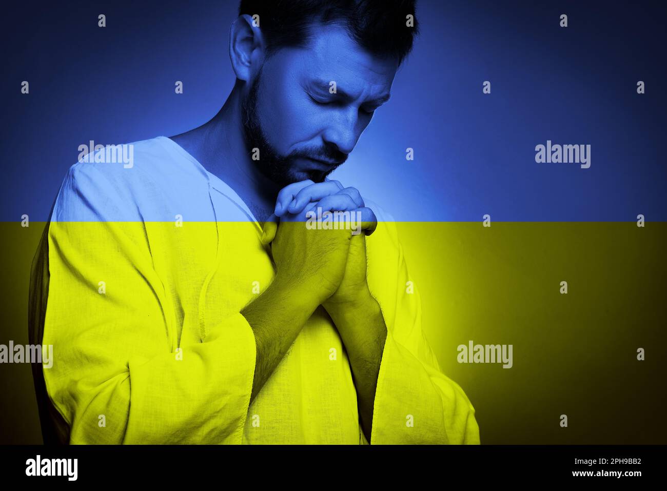 Pregate per l'Ucraina. Doppia esposizione dell'uomo che prega e bandiera nazionale Ucraina Foto Stock
