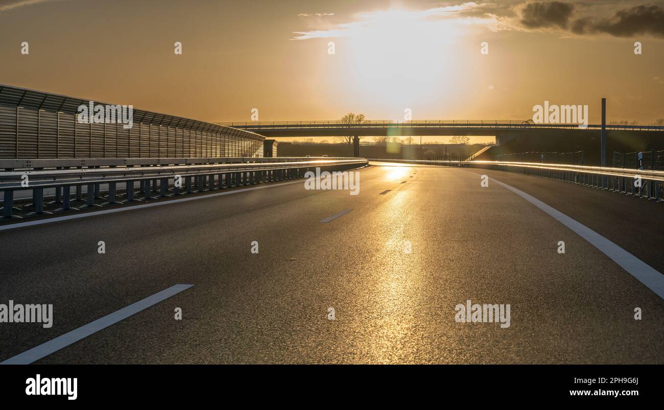 Guida al sole a un Autobahn tedesco. Simbolo per il pericolo di guardare alla luce solare durante la guida. Foto Stock