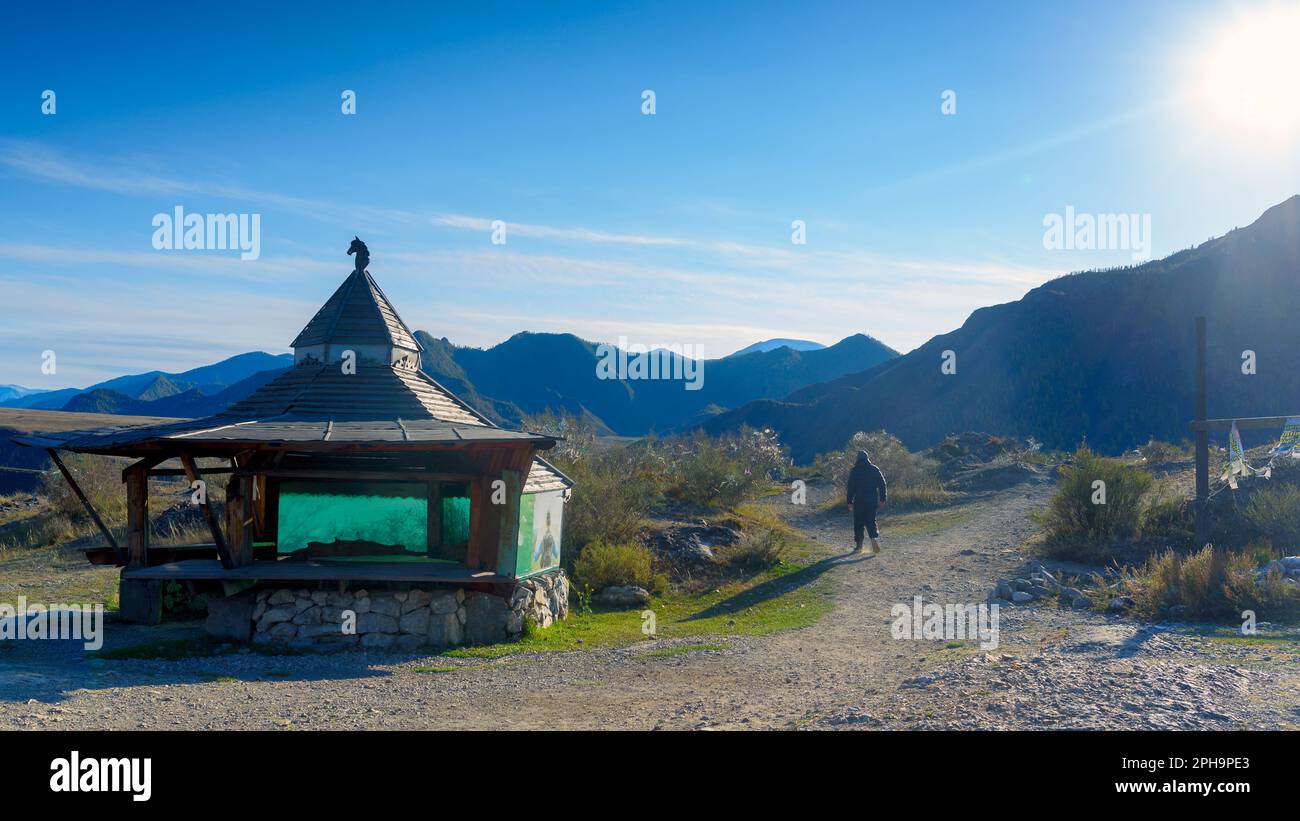 Un turista maschio cammina oltre un gazebo di casa rotonda con una testa di cavallo sul roofto riposo stand abbandonati nei monti Altai Foto Stock
