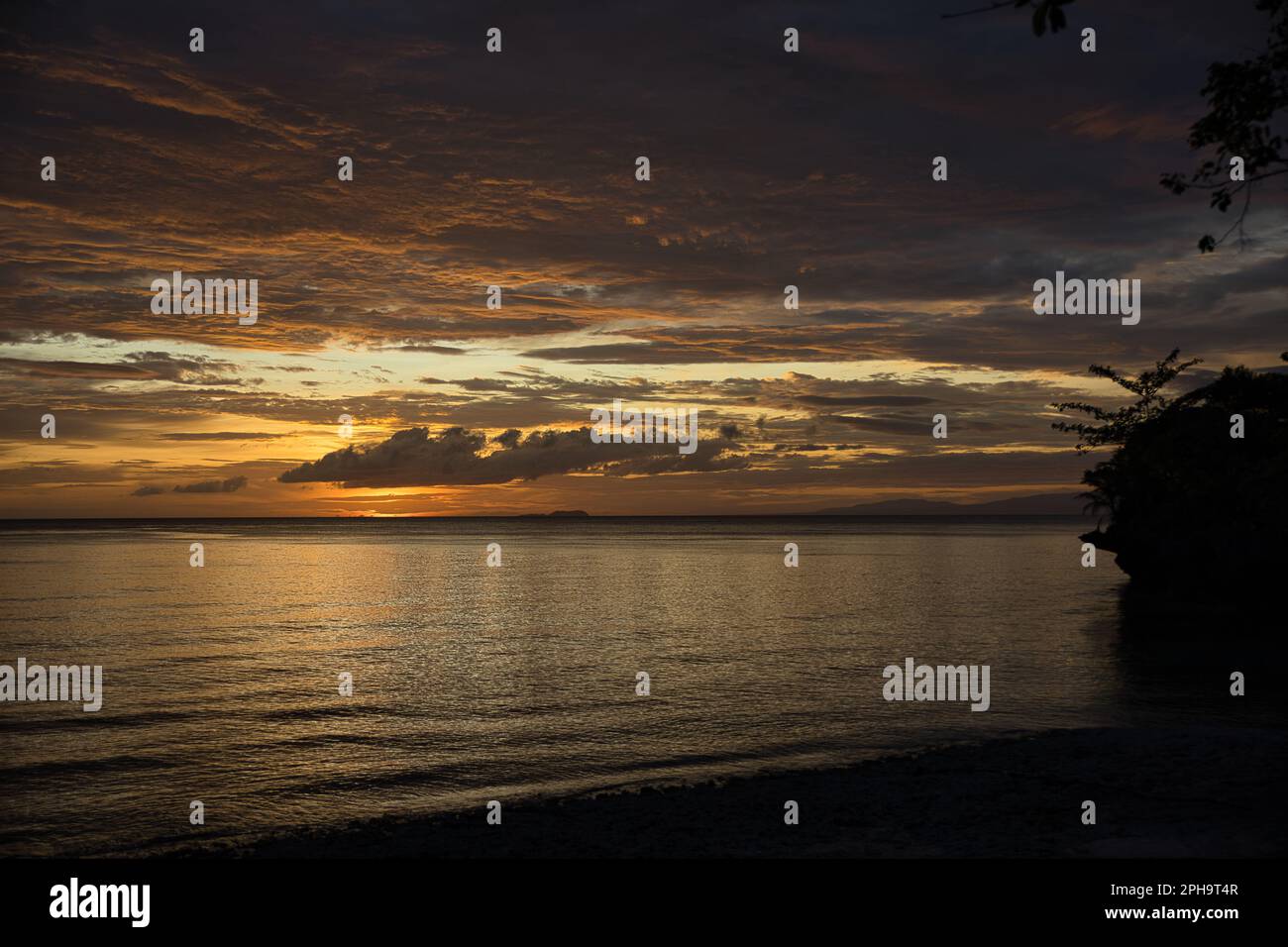 Pittoresco tramonto sulla spiaggia di Siquijor nelle Filippine, tutto il cielo si illumina di colore giallo dorato. Foto Stock