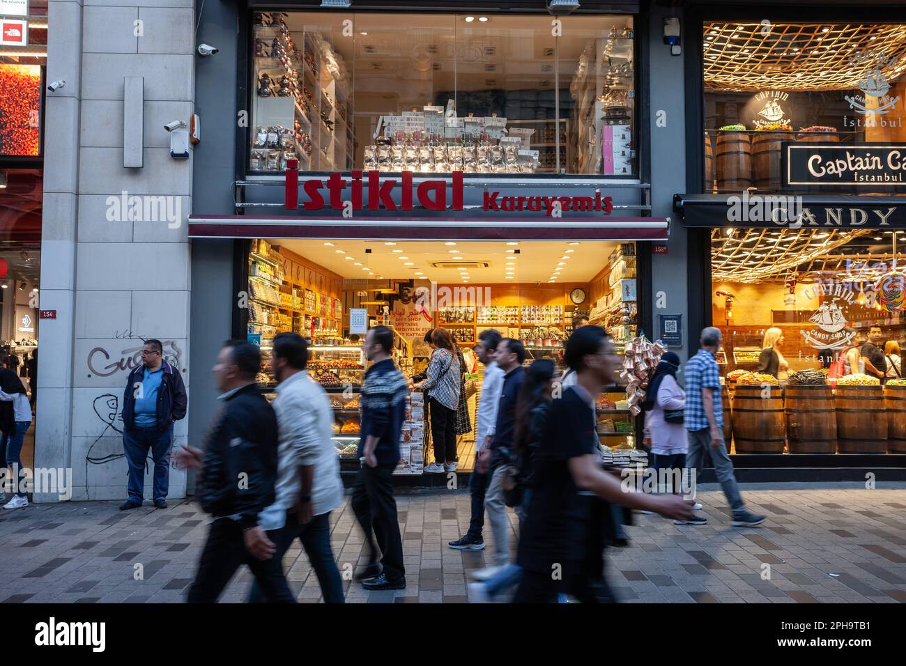 Immagine di una folla di persone sfocate che passano sulla strada istiklal di istanbul, di fronte a un negozio di frutta secca, noci e dolci. Foto Stock