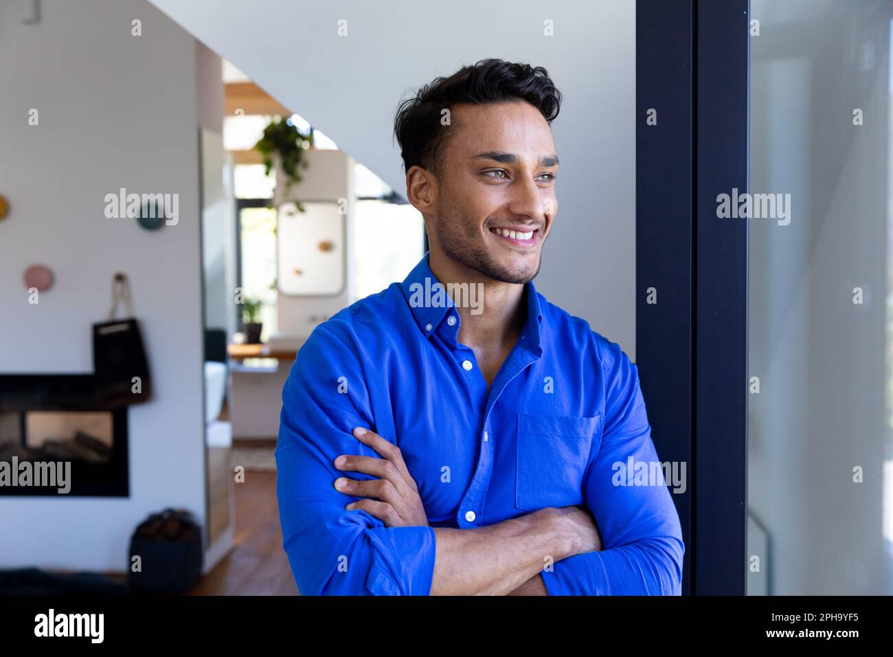 Felice uomo biraciale appoggiato alla finestra e guardando via Foto Stock