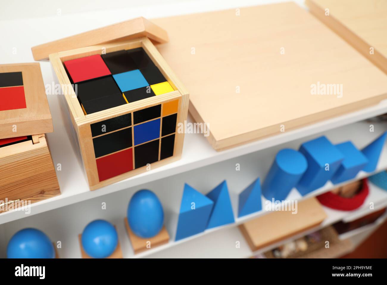 Set di oggetti geometrici in legno e altri giocattoli montessori su scaffali Foto Stock