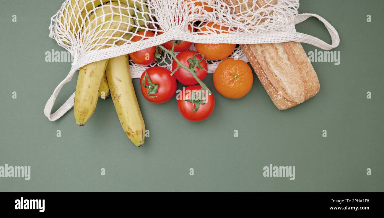 Verdure, frutta, pasta in un vaso di vetro e pane in una borsa della spesa su sfondo verde. Il concetto di vita e di shopping senza sprechi. No Foto Stock