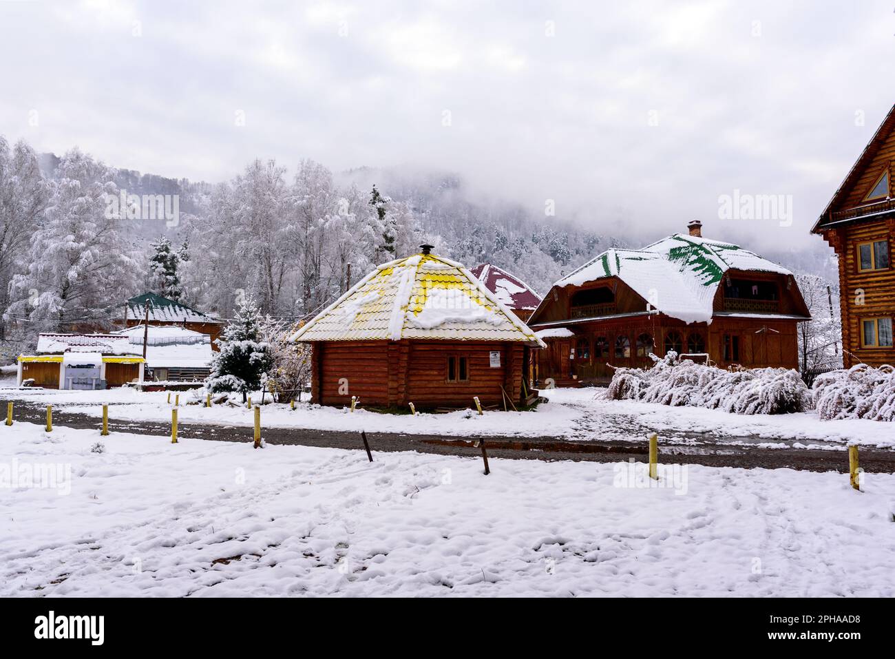 Ayla casa rotonda su un terreno giardino con alberi di betulla sullo sfondo di case in legno nella neve in inverno nella Altai in Siberia. Foto Stock