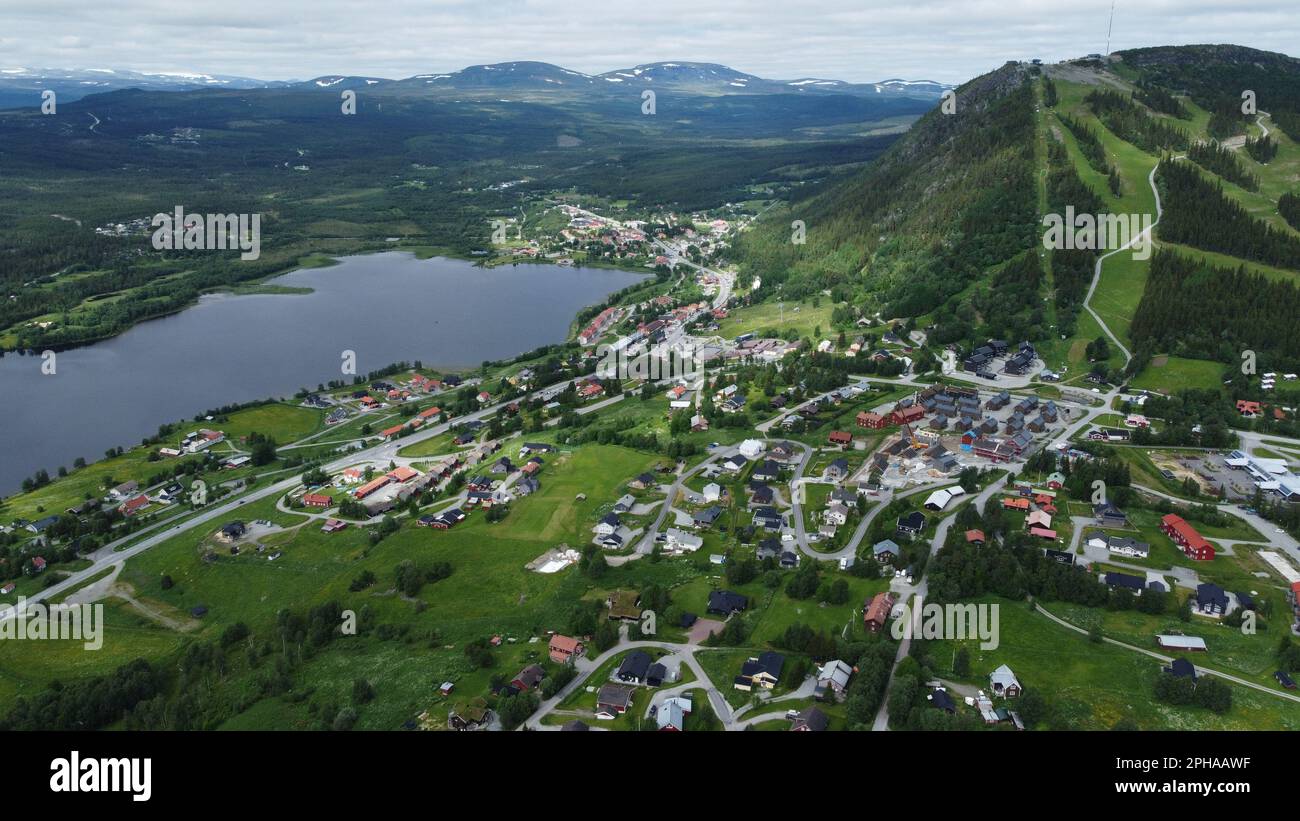 Una vista aerea di una pittoresca città, un lago e montagne boscose Foto Stock